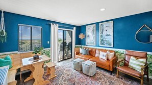Una habitación con una pared azul, un sofá de cuero marrón, una mesa de madera y una alfombra estampada.