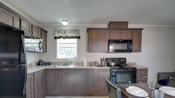 A kitchen with dark wooden cabinets, a black refrigerator, a microwave, and a stove.