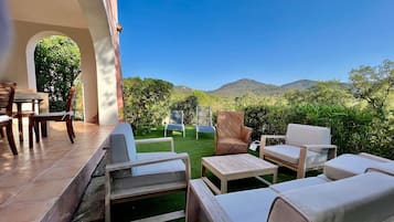 Relax in a serene outdoor space with a patio, sofa, and table, surrounded by a lush lawn and breathtaking mountain views.