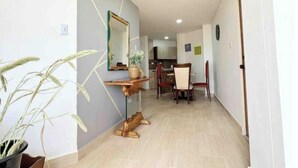 A hallway with a dining area, a wooden table, chairs, a potted plant, and a mirror on the wall. - Modern Apt With View of the Basilica (Guadalajara de Buga)