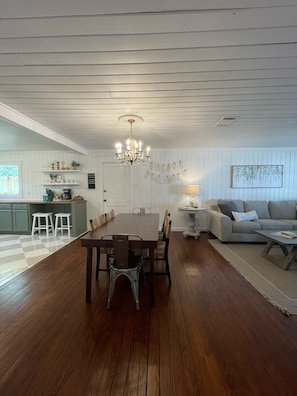 A spacious living area with a wooden dining table, a sofa, and a chandelier. - Charming 3/2 Farmhouse Near Fixer Upper and Gathering Oaks (Crawford)