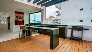 A modern kitchen with a large island, wooden flooring, and a view of the sea. - BRAND NEW PENTHOUSE CONDO IN ROMANTIC ZONE - LISTEN TO THE WAVES (Puerto Vallarta)