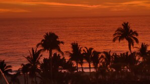 A sunset over the ocean with palm trees silhouetted against the sky. - BRAND NEW PENTHOUSE CONDO IN ROMANTIC ZONE - LISTEN TO THE WAVES (Puerto Vallarta)