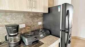 Cozinha com armários de madeira, fogão a gás, cafeteira e geladeira.