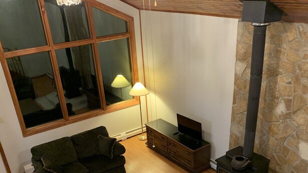 A cozy living room with a fireplace, green sofas, a coffee table, and a stone wall.
