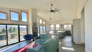 A spacious living area with a large sofa, a dining table, and a kitchen in the background. - Modern Cabin Facing Canaan Valley Ski Slopes (Davis)
