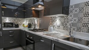 A modern kitchen with dark cabinetry, a microwave, a coffee maker, and a sink. - Whitby Haven (Whitby)