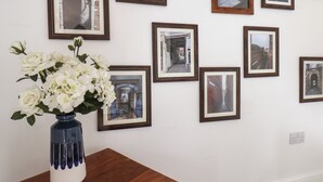 A wall with multiple framed photographs and a vase with white flowers on a wooden table. - Whitby Haven (Whitby)