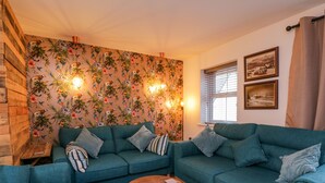 A cozy living room with a teal sofa set, a wooden coffee table, and a tropical wallpaper. - Whitby Haven (Whitby)