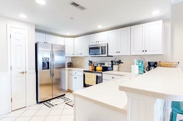 Una cocina moderna con armarios blancos, electrodomésticos de acero inoxidable y una isla central.