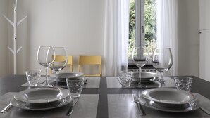 A dining table set with plates, glasses, and cutlery, with chairs and a window in the background. - Giuseppe Pastine 17 D - Santa Margherita Ligure (Santa Margherita Ligure)