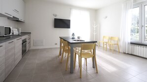 A modern kitchen with grey cabinets, a microwave, and a dining area with a table and chairs. - Giuseppe Pastine 17 D - Santa Margherita Ligure (Santa Margherita Ligure)