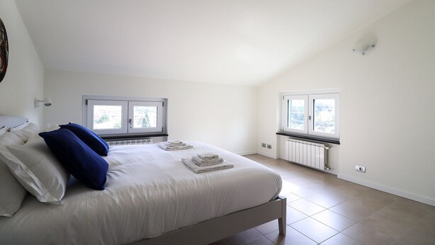A bedroom with a bed, two windows, a radiator, and a light switch. - Giuseppe Pastine 17 D - Santa Margherita Ligure (Santa Margherita Ligure)