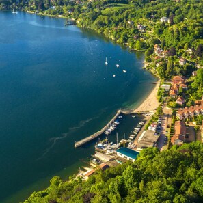 An aerial view of a lakeside town with a marina, residential buildings, and lush greenery. - Casa Amabile With Pool (Leggiuno)