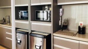 A modern kitchen with stainless steel appliances, including a microwave and a coffee machine, and a trash bin. - Av0806 Studio Avanhandava (São Paulo)