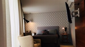 A bedroom with a bed, bedside tables, a chair, a lamp, and a TV mounted on the wall. - Av0806 Studio Avanhandava (São Paulo)