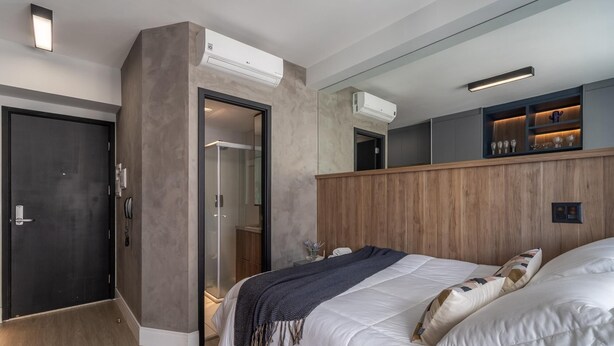Una habitación de hotel moderna con una cama grande, un vestidor amplio y unidades de aire acondicionado integradas.