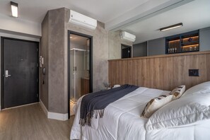 A modern hotel room with a large bed, a walk-in closet, and built-in air conditioning units. - Setinluz1103 Studio Luz (São Paulo)