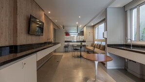 Una cocina moderna con un muro decorativo de madera, un televisor integrado y una zona de comedor con una mesa redonda y sillas.