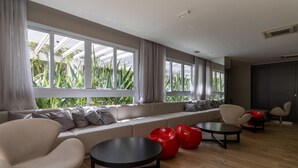 Un área de descanso moderna con un sofá, sillones de peluche rojos y una mesa redonda.