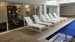 A poolside area with white lounge chairs, a pool, and a gym visible through glass doors. - Hype055 in S o Paulo (São Paulo)