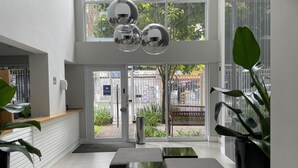 A modern lobby with a reception desk, seating area, and large windows offering a view of the street. - Hype055 in S o Paulo (São Paulo)