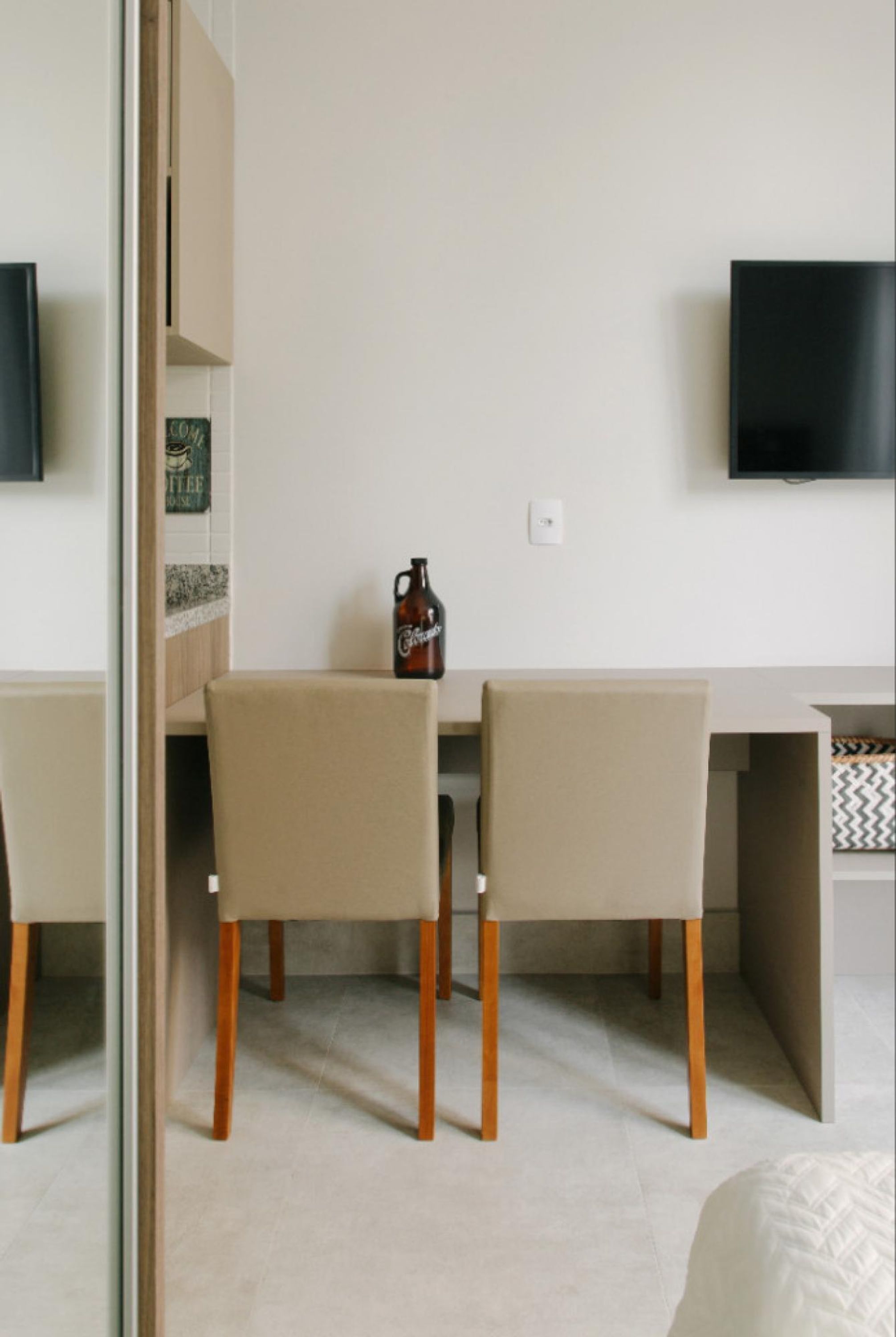 Une chambre moderne équipée d’un bureau, de deux chaises, d’une télévision et d’une bouteille de bière posée sur le bureau.