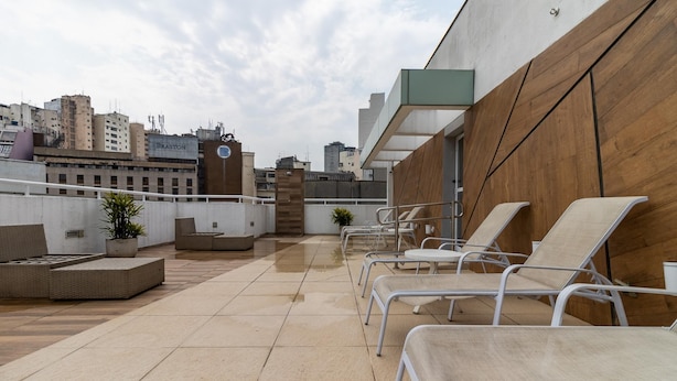 Una terraza en la azotea con sillones, una zona de estar pequeña y vistas a la ciudad.