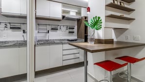 Una cocina moderna con armarios blancos, una encimera de granito y un taburete rojo.