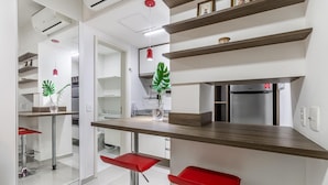 Una cocina moderna con encimera de madera, taburetes rojos y un refrigerador empotrado.