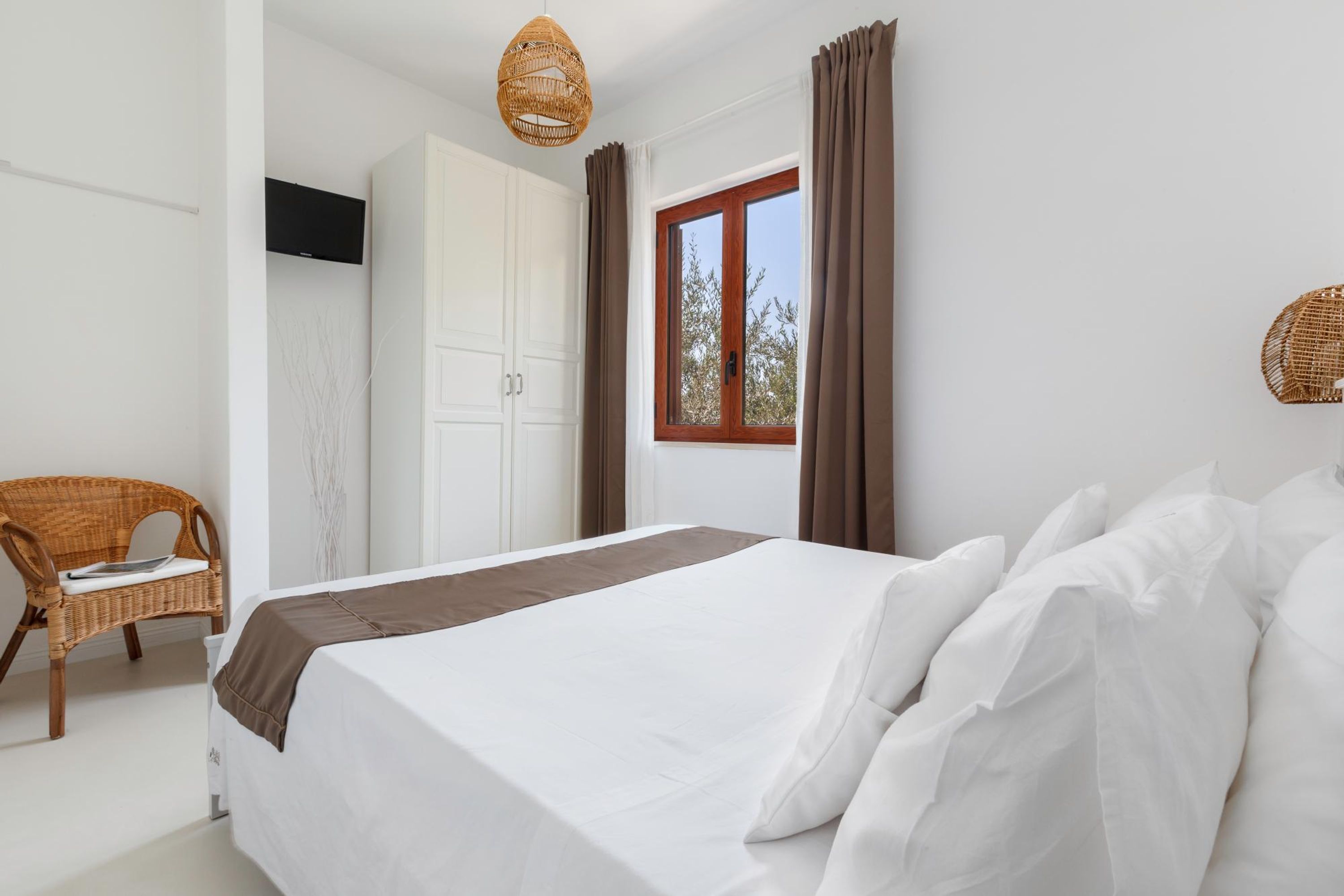 Une chambre à coucher avec un lit, une chaise, une armoire et une fenêtre avec des rideaux.