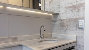 A bathroom with a marble sink, a modern faucet, and a white tiled wall. - Av0703 Studio Avanhandava (São Paulo)