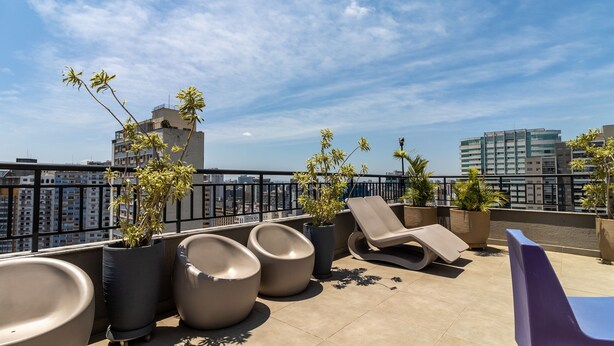 A rooftop terrace with lounge chairs, potted plants, and a city view. - Ycp2101 in S o Paulo (São Paulo)