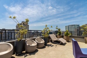 A rooftop terrace with lounge chairs, potted plants, and a city view. - Ycp2101 in S o Paulo (São Paulo)