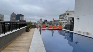 A rooftop pool with a tiled edge, surrounded by a wooden deck and a metal railing. - Ycp2101 in S o Paulo (São Paulo)