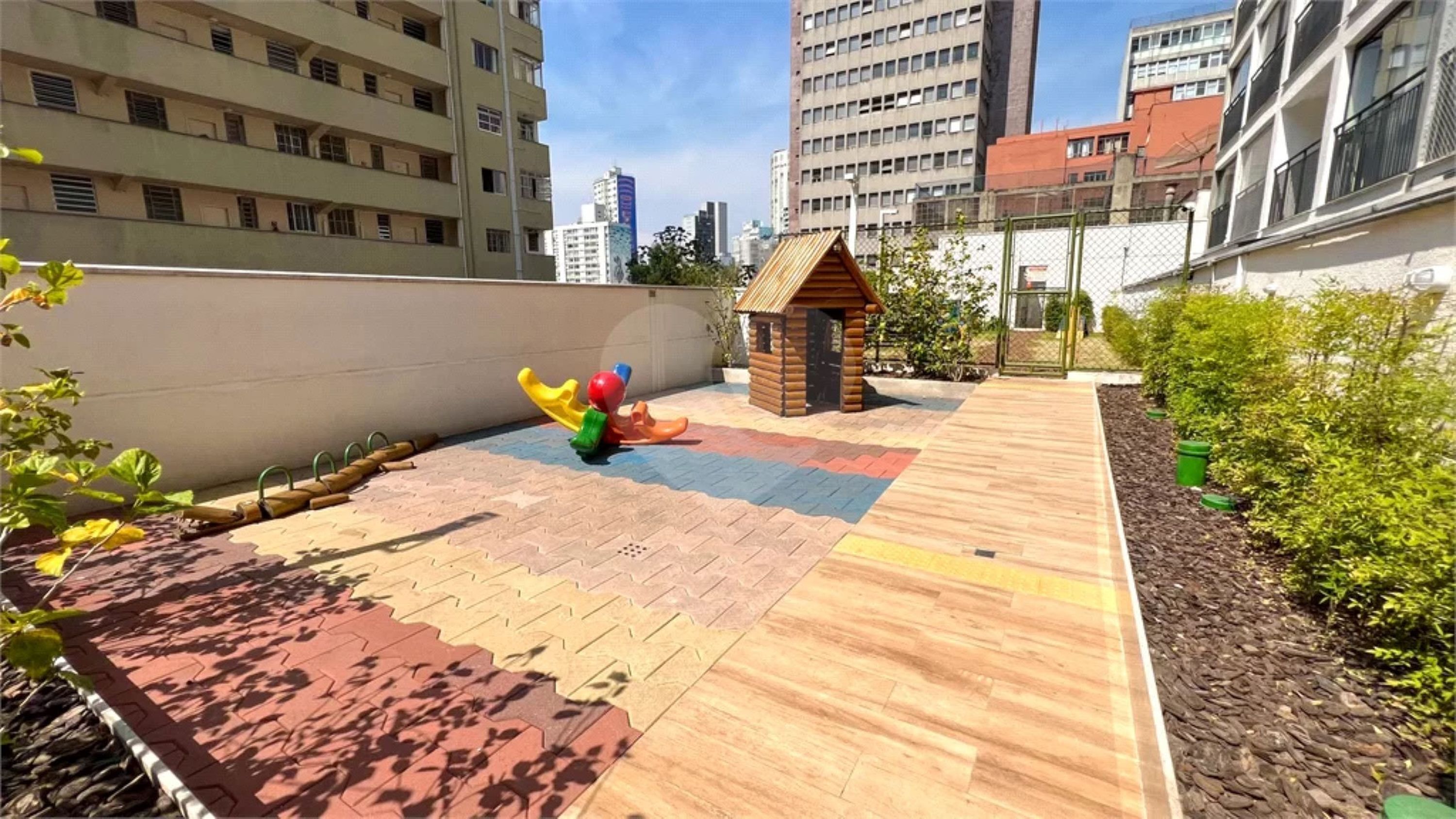 Een dakterras met een speeltuin, glijbaan, klimgedeelte en een klein houten huisje.
