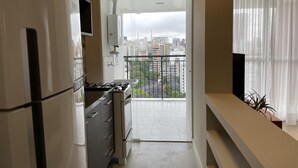 A modern kitchen with a gas stove, a refrigerator, and a view of a cityscape through a balcony. - Ycp2101 in S o Paulo (São Paulo)