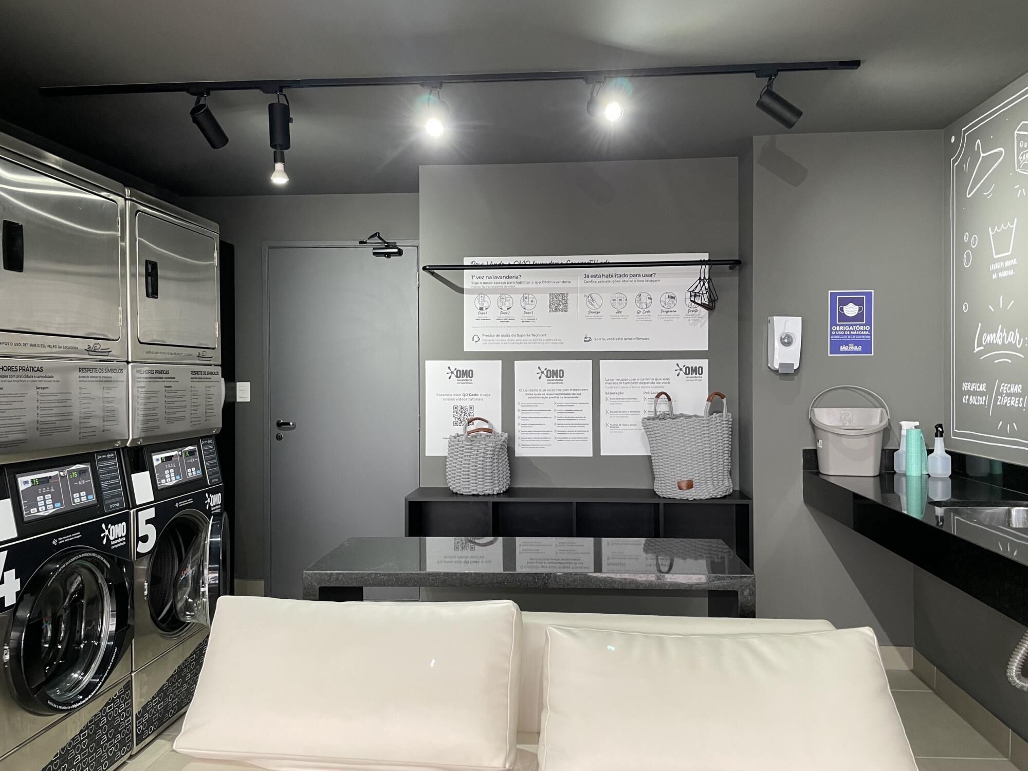 A hotel room with a washing machine, a sink, and a mirror with instructions.
