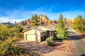 A residential area with houses, a paved driveway, and a mountain backdrop. - 45 Grasshopper Lane, Sedona · Red Rock Views, Hot Tub, New & Modern, Walk To All (Sedona)