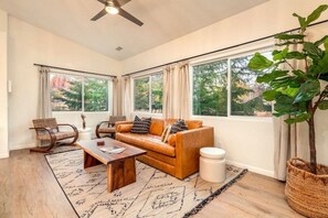 A living room with a sofa, coffee table, and a large window with curtains.