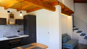 A modern kitchen with a wooden ceiling, a built-in stove, and a wine shop sign. - Our Happy Place Detached vacation home with garden (Mandello del Lario)