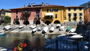 A waterfront building with multiple balconies and a dock with boats. - Our Happy Place Detached vacation home with garden (Mandello del Lario)