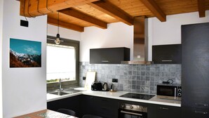 A modern kitchen with a wooden ceiling, a large window, and a view of mountains. - Our Happy Place Detached vacation home with garden (Mandello del Lario)