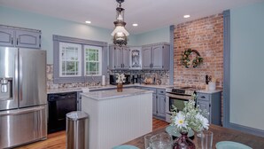 Una cocina moderna con electrodomésticos de acero inoxidable, una isla central y una pared de ladrillo decorativa.