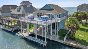 Une propriété située au bord de l’eau, dotée d’une terrasse couverte, de chaises longues et offrant une vue sur la mer.