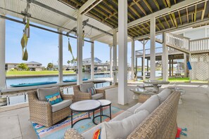 An outdoor covered patio with wicker furniture, a pool view, and a clear sky. - Relax, Play, Fish, Crab - Birds, Beach and incredible Sunsets - Sleeps 10 to 11 (Galveston)