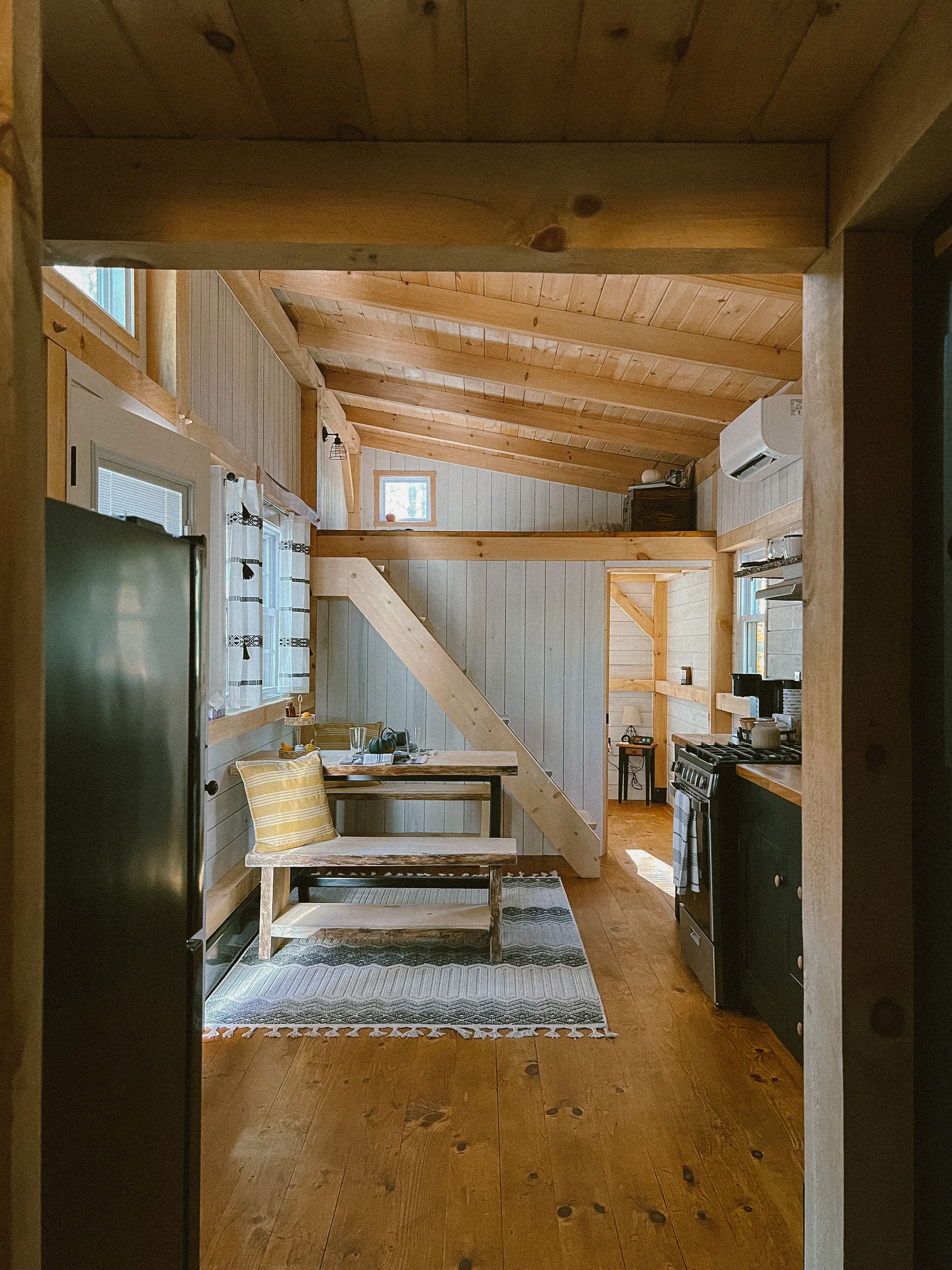 Un intérieur rustique en bois comprenant une cuisine, un coin repas et un escalier.