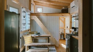 A rustic wooden interior with a kitchen, dining area, and a staircase. - COZY PSU Rustic Tiny Home and Fishing Retreat (Petersburg)