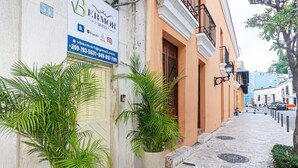A hotel with a signboard, potted plants, and a cobblestone street. - VBermor Hotel (Santo Domingo)