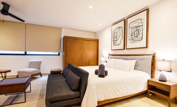 Une chambre d’hôtel comprenant un lit, un canapé, un bureau, une chaise et deux œuvres d’art accrochées au mur.